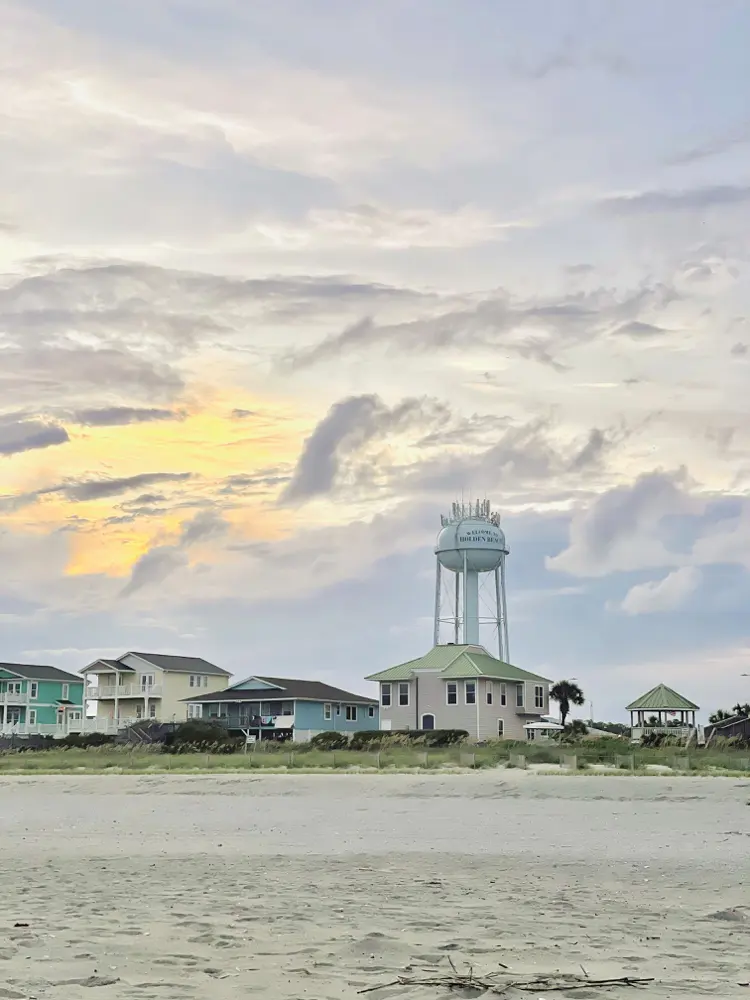The Holden Beach water tower rising above the beachfront homes at dusk