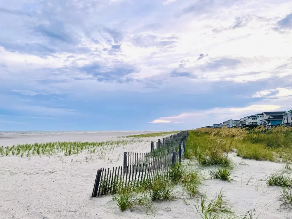 Dune fence and beach houses along the shoreline on Oak Island